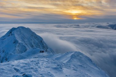 Kışın dağ ve bulutların üzerinden günbatımı