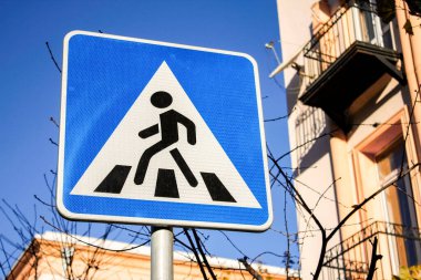 Zebra, parlak güneş ışığı altında yol tabelasını geçiyor..