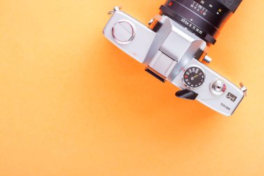 Turuncu zemin üzerinde 35 mm 'lik klasik slr film kamerası ve metin için boş alan.