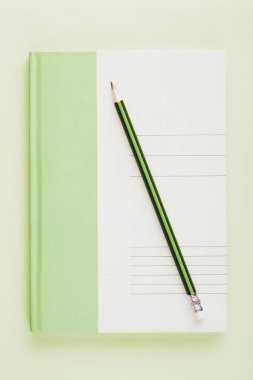 Kalemle birlikte yeşil beyaz defter. Ticari eğitim minimalist konsept düz yatıyordu.
