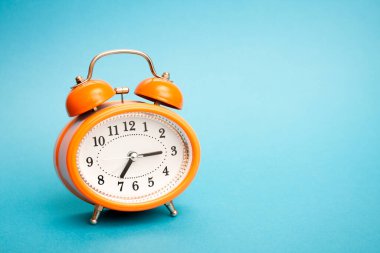 Mavi arkaplanda zilleri olan klasik turuncu alarm saati ve metin için ücretsiz kopyalama yapıştırıcı alanı.