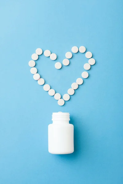シンプルな薬と医療の概念フラットレイアウト 錠剤で作られた白いペットボトルとハート型のレイアウト ストック写真