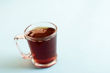 Pastel mavi arka planda bir bardak siyah çay..