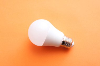 Turuncu arka planda beyaz ekonomi ampulü.