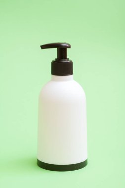 Yeşil arka planda siyah tabanlı plastik sabun şişesi..