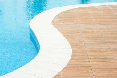 Parlak güneş ışığı altında temiz mavi suyla yüzme havuzu.