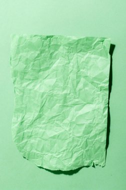 Minimal still life image of a crumpled piece of green paper.