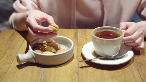 Frau in rosa Kapuzenpulli isst russisches Dessert - Nüsse mit Kondensmilch genannte Kekse. — Stockvideo