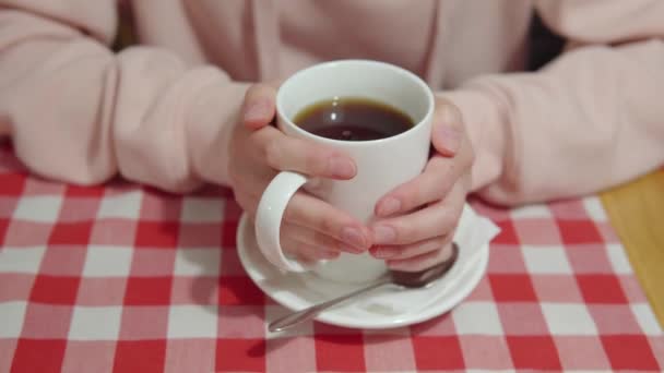 Een meisje bezoeker van het café houdt een mok warme thee met stevia of rietsuiker met haar handen. — Stockvideo
