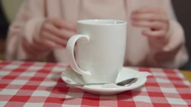 Masadaki kadın elleri çay ile seramik bardağı tutuyor.. 