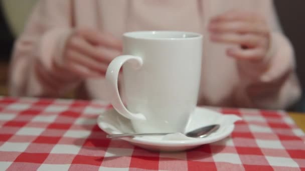 Las manos femeninas en la mesa sostienen la taza de cerámica con un té. — Vídeo de stock