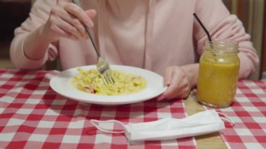 Soslu, karidesli, kiraz domatesli ve fesleğenli balkabaklı makarna yiyen kadın..