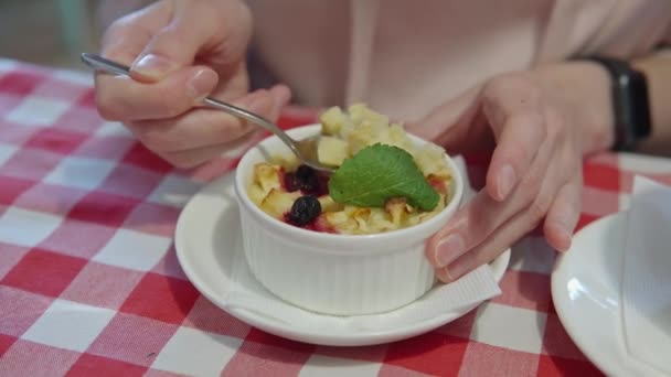 Mujer comiendo pudín con manzana, calabaza y bayas, bebiendo té en un café. — Vídeos de Stock