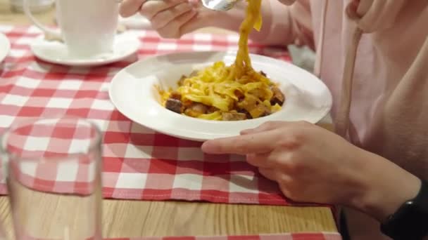Mulher comendo massas apetitosas com medalhões de porco, queijo e cogumelos trompete. — Vídeo de Stock