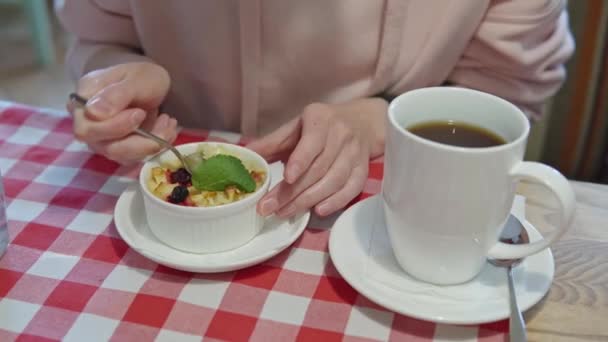 Chica joven comiendo delicioso pudín con manzana, calabaza y cáscara de naranja, beber té negro en un café. Imágenes de 4k. — Vídeos de Stock