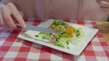 Kadın taze bezelye, havuç, lahana, salatalık ve jambon salatası yiyor..