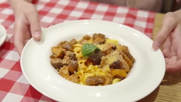 Mujer muestra una pasta con medallones de cerdo, queso parmesano y champiñones trompeta. — Vídeo de stock