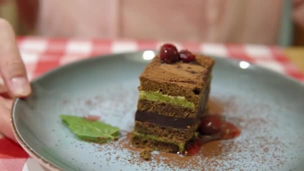 Ciasto warstwowe z matcha zielonej herbaty i ciemnej czekolady na talerzu. Kobiece ręce pokazują deser.. — Wideo stockowe