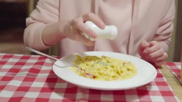 Женщина добавляет соль или перец в тыквенную пасту с креветками, помидорами черри и базиликом. — стоковое видео