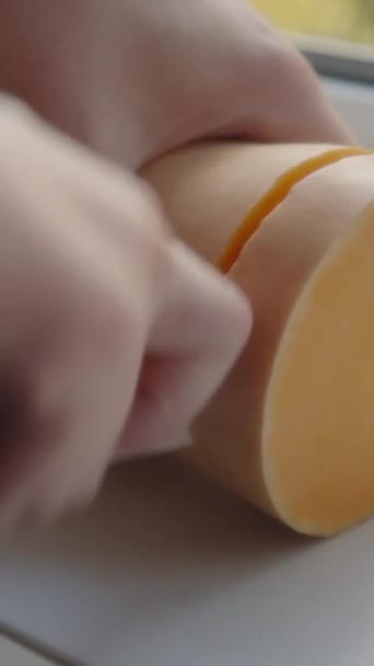 Vídeo vertical para redes sociais: chef corta fatia, um pedaço de manteiga de abóbora com uma faca de cerâmica na placa da cozinha. Close-up.Vídeo vertical para redes sociais: o chef corta fatia, um — Vídeo de Stock