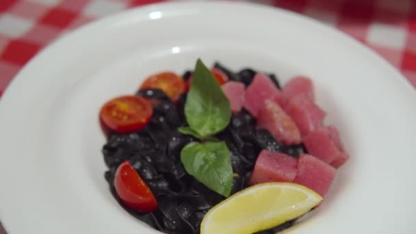 Appetizing black pasta with cuttlefish ink, raw tuna and vegetables. — Stock Video