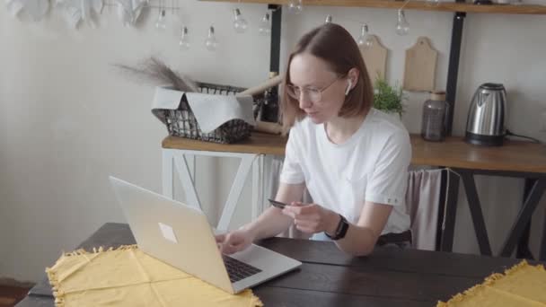 Kredi kartı tutan ve dizüstü bilgisayar kullanan genç bir kadın.. — Stok video