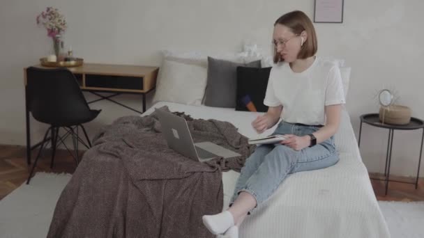 Молода біла жінка дивиться на ноутбук, який навчається з дому . — стокове відео