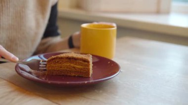 Bir kafedeki kadın, Medovik denilen katmanlı ballı pasta yiyor.. 