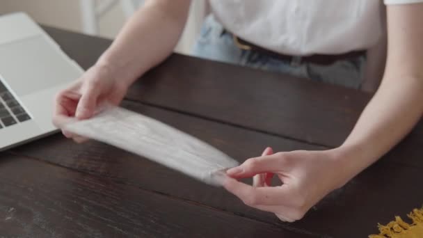 A close-up of female hands opening a medical protective mask out of a package. — Stockvideo