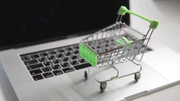 Een speelgoed groene lege metalen kar staat op een touchpad, het lichaam van een laptop. — Stockvideo