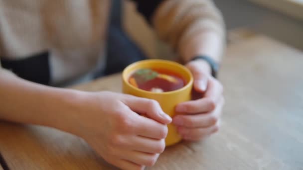 Крупним планом знімок жіночих рук на жовтій чашці гарячого цитрусового чаю . — стокове відео
