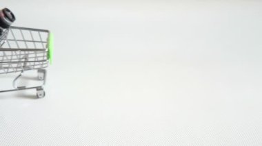 Minyatür alışveriş arabasında beyaz ya da açık gri arka planda yeşil renkli oyuncak plastik kamera.. 