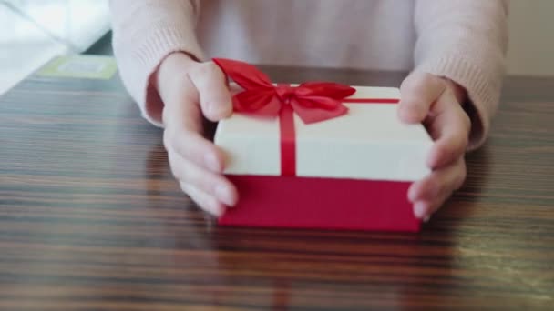 Dziewczyna prezentuje prezent w czerwono-białym pudełku. Koncepcja Walentynki, urodziny, wakacje, rocznica, 8 marca, Dzień Matki, Boże Narodzenie, Nowy Rok, dzień kobiety, Święto Dziękczynienia. Widok z bliska. — Wideo stockowe