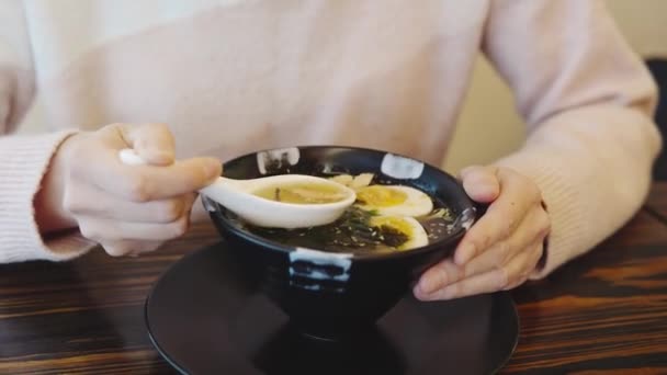 Flickan äter misosoppa med kyckling på en japansk restaurang. Närbild av att äta asiatisk mat. — Stockvideo