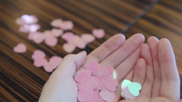 Konzept des Valentinstages. Viele rosa Herzen in den Händen der Mädchen. Großaufnahme von dekorativem Konfetti in Herzform in Frauenhänden. — Stockvideo
