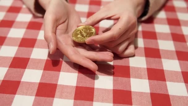 Eine Bitcoin-Goldmünze in weiblichen Händen aus der Nahsicht. Weltweit digitales Geld. Konzept der Kryptowährung. — Stockvideo