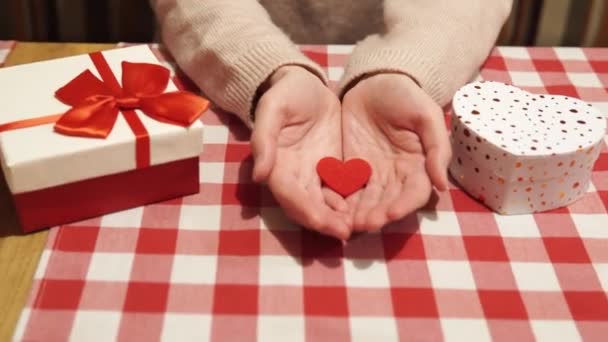 愛の象徴に焦点を当てた滑らかなズームカメラ-若い魅力的な女性の手のひらに赤いハートイオン。バレンタインデー、結婚、愛の宣言、婚約、記念日の概念 — ストック動画