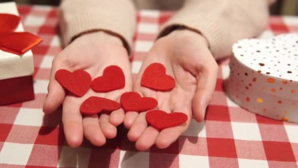 女の子のヤシのいくつかの赤い心。バレンタインデー、女性の手でお祝いの装飾、お祝いの準備、家の装飾を祝う属性。背景にある贈り物. — ストック動画