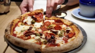 Kız bir parça sulu, acı biberli pizza alıp tabağına koyuyor..