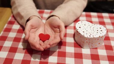 Kamerayı, içinde aşkın sembolü olan kadın avuçlarına ve Sevgililer Günü 'nün kırmızı kalbine yakınlaştırıyorum. Bir yıldönümü hediyesi ya da kalp şeklinde bir kutuda nişan.. 