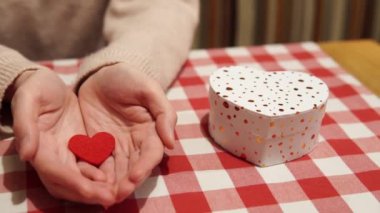 Genç kızın elinde aşkın sembolü olan kırmızı bir kalp, yanında kalp şeklinde bir kutuda bir hediye var. Bir randevuda romantik bir an. 