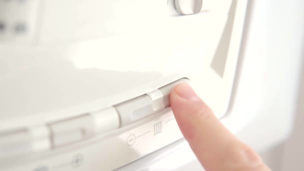 Man justerar temperaturen på hemgaspannan för varmvatten och uppvärmning. Styr systemet med knappar och digital display. — Stockvideo