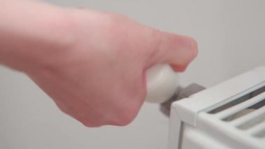 Bir kadının eli akünün sıcaklığını sıcaklık kontrolörüyle ayarlar. Ev ısıtma sistemi. 
