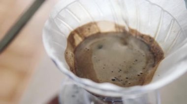 Barista huniye sıcak su döker, kağıt filtresini ıslatır.. 