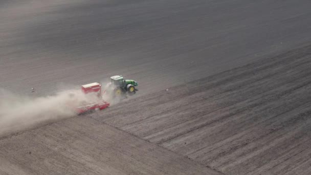 Traktor sådd utsäde på plöjd åker. Såmaskiner på åkern. Utsäde i jordbruksmark, vy från luften. — Stockvideo