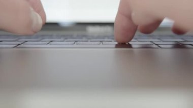 Laptop klavyesine yazı yazan bir kişinin yakın plan görüntüsü.