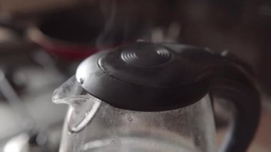 İçeride buharlı elektrikli su ısıtıcısı var, yakın plan. Ev mutfağındaki çaydanlıktan buhar çıkıyor..