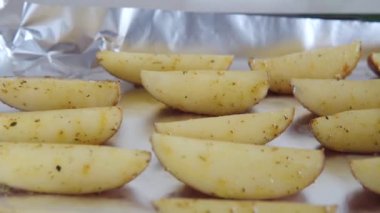Baharatlı fırında patates dilimleri, otlu, fırında sade patatesler, folyoyla yakın plan. 4k görüntü.