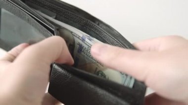 Adamın biri cüzdanında 100 dolarlık banknot gösteriyor. Tasarruf, bütçe, yatırım, finans kavramı.