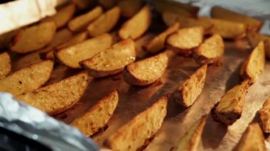Fırınlanmış patates dilimleri ve kırsal baharatlar, folyoyla yakın plan çekimde, 4k.